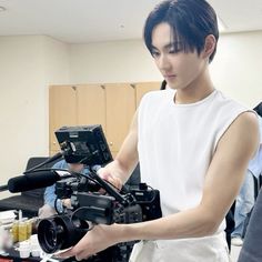 a young man holding a camera in front of a recording equipment set up on a table