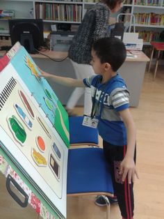 a young boy standing in front of a table with an easel on top of it