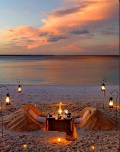 a table set up on the beach with candles