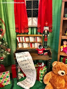 a teddy bear sitting in front of a christmas tree with presents on the floor and other holiday decorations