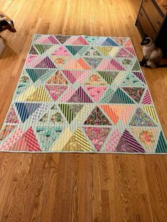 a dog sitting on the floor next to a quilt