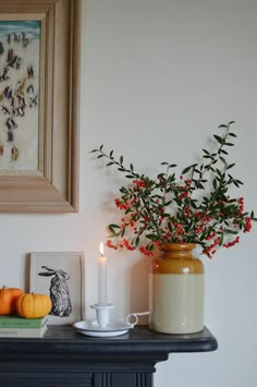 there is a vase with berries on the table next to a candle and some books