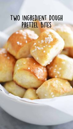 a white bowl filled with bread rolls covered in sesame seeds and sea salt on top of a gray surface