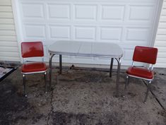 two red chairs and a table in front of a garage door