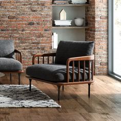 two chairs and a rug in front of a brick wall with bookshelves on it