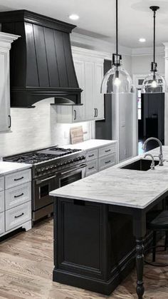 a kitchen with black and white cabinets, marble counter tops, and stainless steel appliances