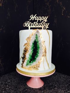 a white cake with gold and green decorations