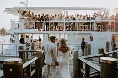 a bride and groom are walking on the dock towards their wedding party as they exit the boat