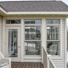 a white chair sitting on top of a wooden floor next to a window covered porch