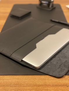 a tablet and pen sitting on top of a black leather pad with a silver cover