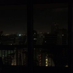 the city lights are lit up in the night sky from an apartment balcony at night