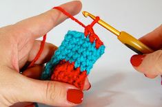 two hands crocheting an object with red and blue yarn