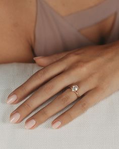 a woman's hand with a diamond ring on her left hand, resting on a pillow