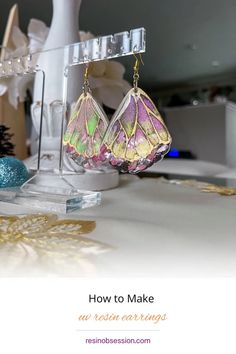 a pair of colorful earrings hanging from hooks on a table with christmas decorations in the background