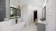 a white bathroom with a large bathtub next to a sink