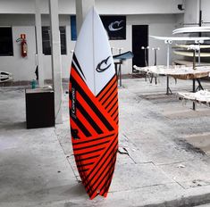 an orange and black surfboard is in the middle of a room full of tables