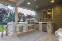 an outdoor kitchen with stainless steel appliances and grilling area next to the back door