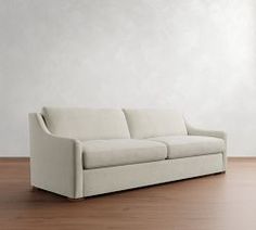 a white couch sitting on top of a hard wood floor next to a wall in an empty room