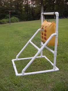 a small white structure in the grass with a yellow bag hanging from it's side