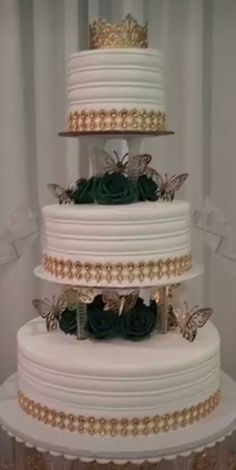 a three tiered wedding cake with green flowers on the top and gold trimmings