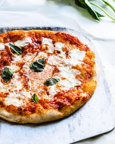 a pizza sitting on top of a metal pan covered in cheese and spinach leaves