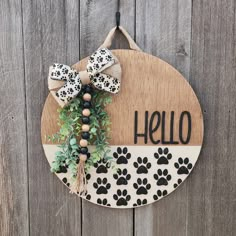 a wooden sign that says hello with black and white paw prints