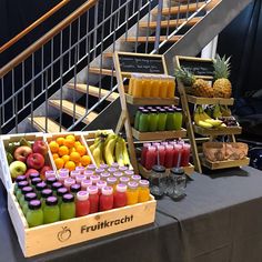 fresh fruit and juices are on display in front of the stairs at an event