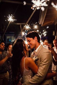 a bride and groom kissing in front of sparklers