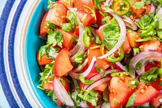 a salad with tomatoes, onions and cilantro in a blue bowl