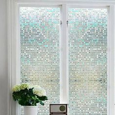 a vase with flowers sitting next to a window covered in frosted glass blocks and beads