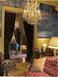 a fancy living room with chandelier, couch and chair in front of a painting on the wall