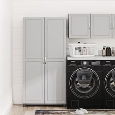 a washer and dryer in a small room with white tile flooring, gray cabinets, and wooden floors