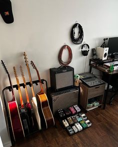 guitars and amps are lined up on the floor in front of a guitar rack