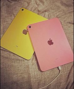 two different colored ipads sitting next to each other on top of a bed together