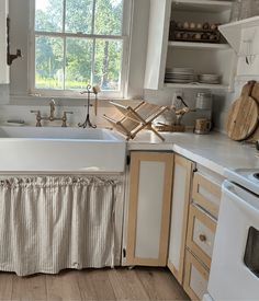 a kitchen with white appliances and wooden cabinets, including a large window over the sink