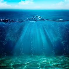 an underwater view of the ocean with blue water and sunlight shining down on the surface