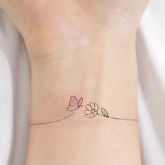 a small tattoo on the wrist of a woman's left arm with flowers and leaves