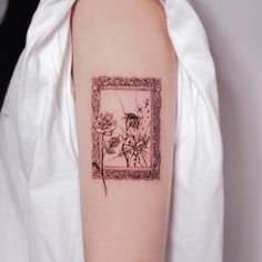 a woman's arm with a tattoo on it that has flowers in the frame