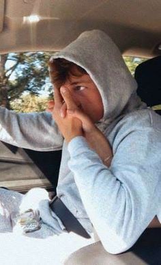 a young boy sitting in the back seat of a car with his hand on his face