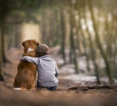 a boy hugging his dog in the woods