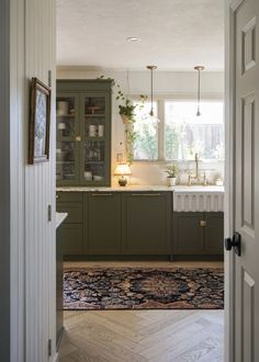 an open door leading to a kitchen with green cabinets