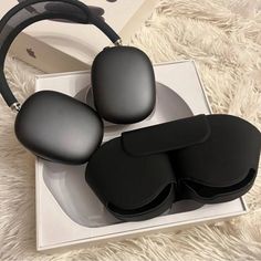 three black glasses in a white box on a furry carpeted surface with headphones