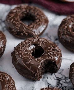 there are many chocolate donuts on the table