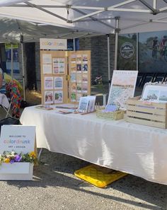 an outdoor market with various items for sale on the table and people looking at them