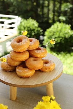 a stack of doughnuts sitting on top of a wooden table next to yellow flowers