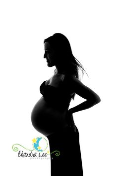 a pregnant woman standing in silhouette with her hands on her hips