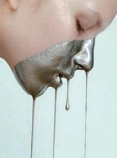 a woman's face is covered in silver liquid