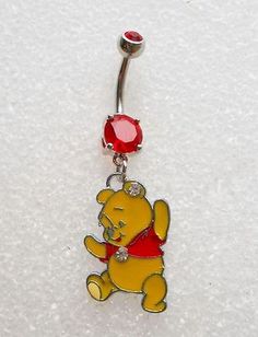 a winnie the pooh belly ring with a red jewel