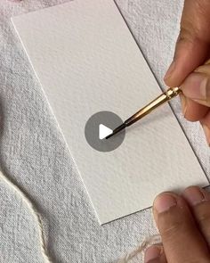 someone is cutting out a piece of white paper with a pair of scissors on it