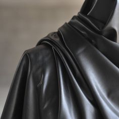 a black leather coat is shown in close up, as if it were draped over